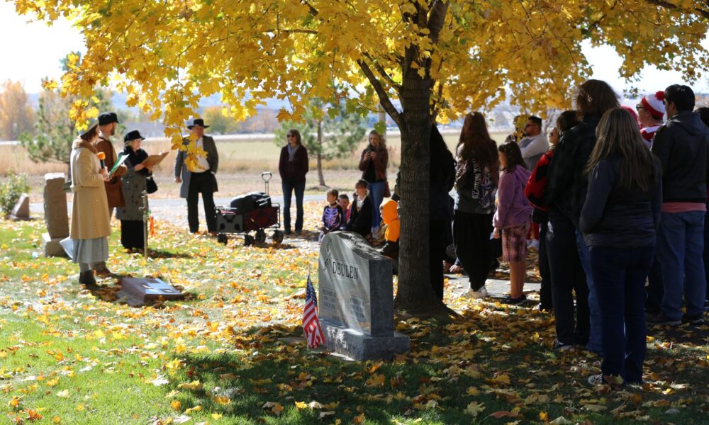 A group of attendees standing around a gravesite listening to actors depicting the life of a past Johnstown resident.