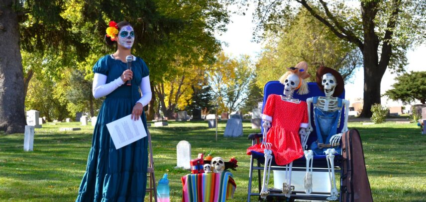 A female actor in colorful costume speaks into a microphone amid themed props at the Johnstown Historical Society’s Cemetery Crawl event.