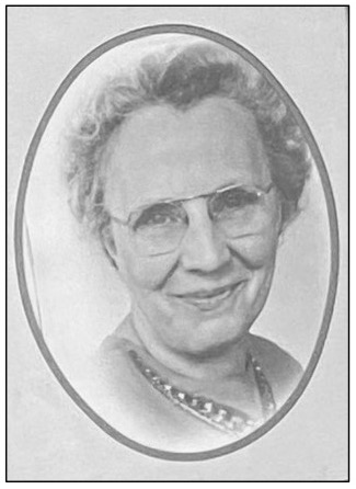 An old black-and-white close-up photograph of Elsie D. Grant, a school nurse, smiling with short wavy hair, metal-rimmed glasses, and a shiny necklace.