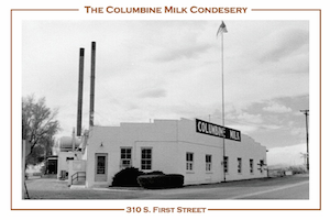 A postcard of The Columbine Milk Condensery located at 310 S. First Street.  The building is white with a graduated roof and large sign that reads, "COLUMBINE MILK".