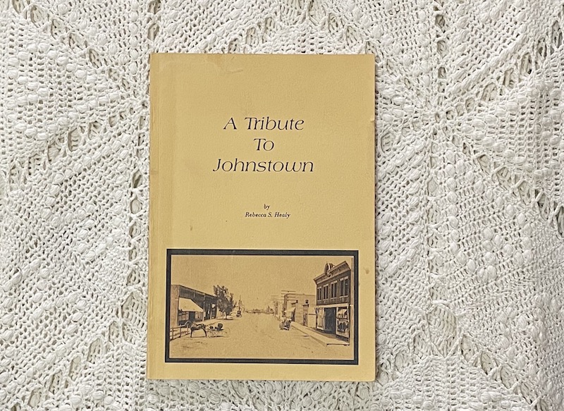 A photo of an older book titled, "A Tribute To Johnstown" by Rebecca S. Healy. The cover features and old photo of Johnstown's main street.